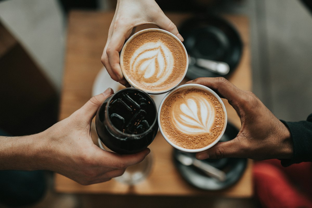 Coffees raised together over a wooden table