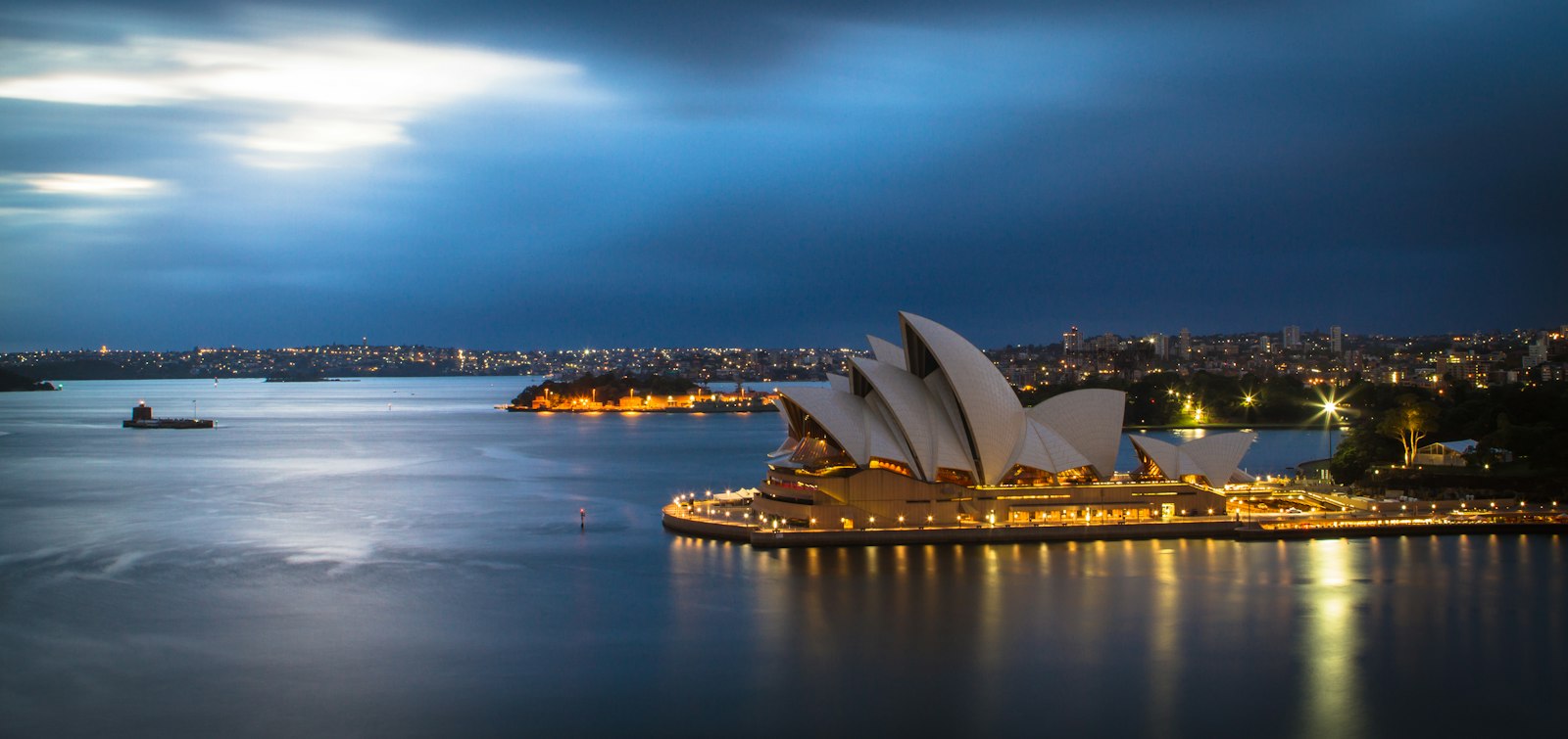 Sydney Opera House glowing on the harbour at dusk